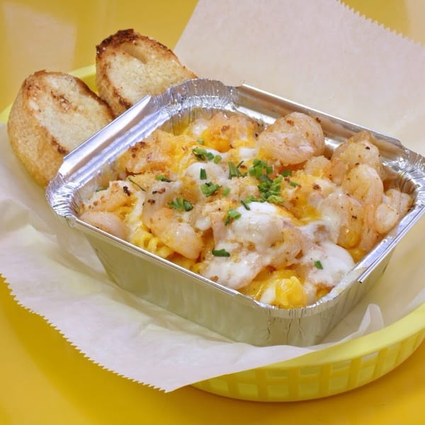 Shrimp mac and cheese in a foil container with two pieces of toasted bread.