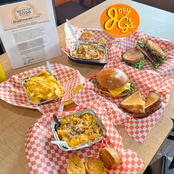 A table laden with various dishes from Joey G's, including mac and cheese, burgers, and sandwiches.