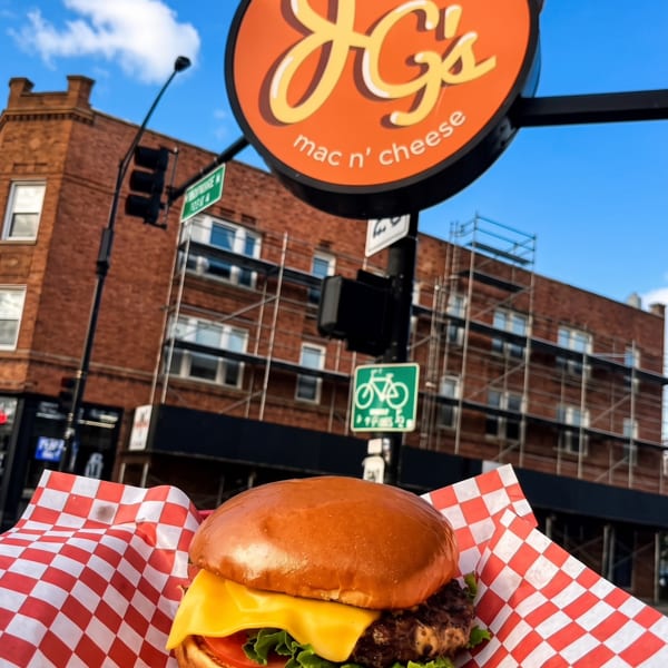 Cheeseburger in a red and white checkered wrapper, with the Joey G's Mac n' Cheese sign above.