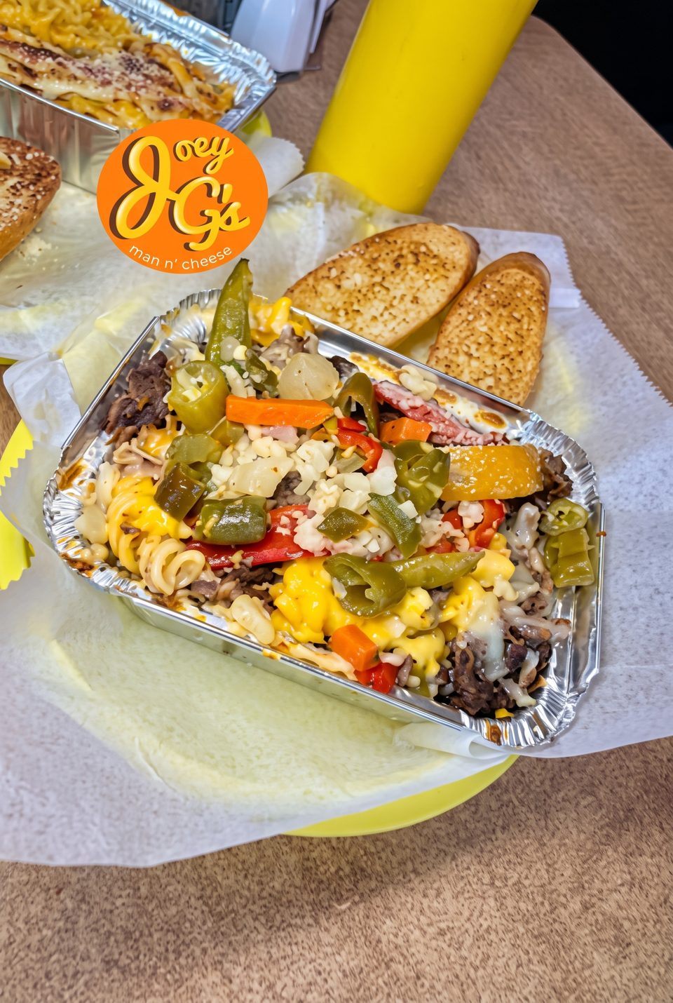 Joey G's Man n' Cheese with beef, peppers, and onions, served with garlic bread.